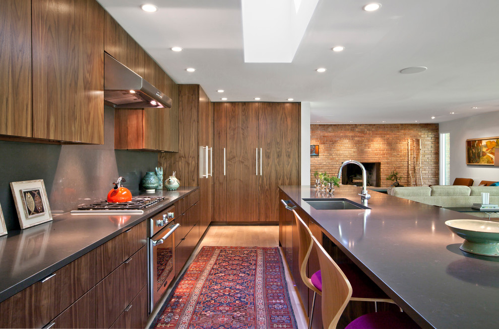 Photo of a mid-sized midcentury galley eat-in kitchen in Indianapolis with an undermount sink, flat-panel cabinets, medium wood cabinets, quartz benchtops, grey splashback, stone slab splashback, stainless steel appliances, light hardwood floors, with island and beige floor.