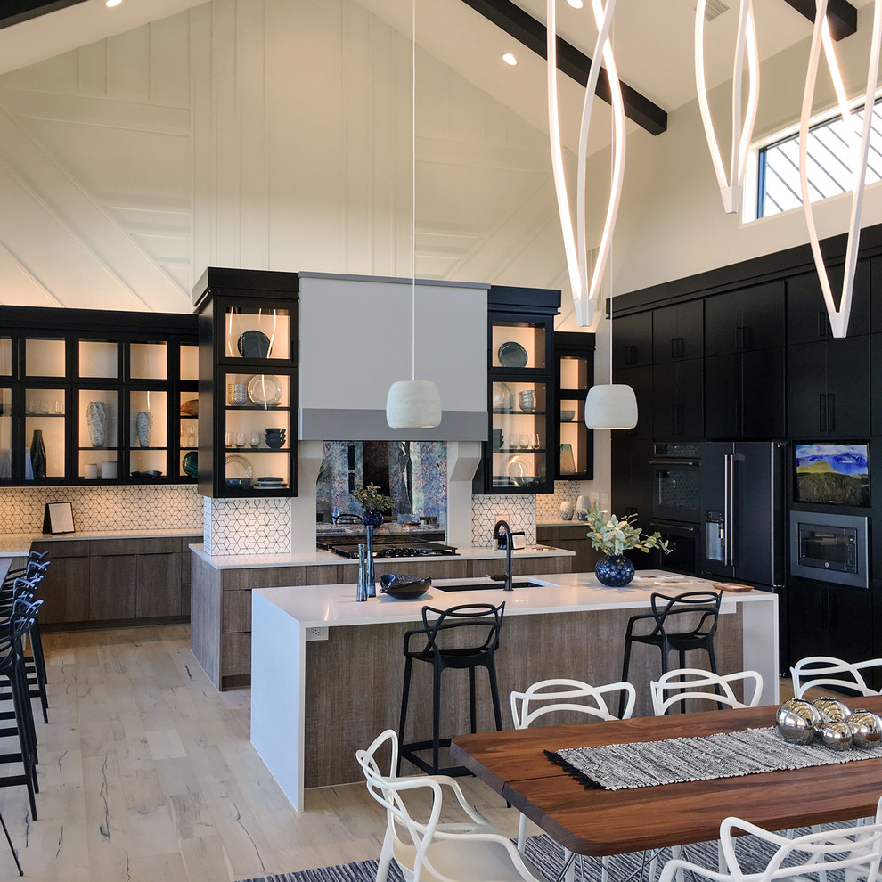 Country u-shaped eat-in kitchen in Austin with an undermount sink, flat-panel cabinets, black cabinets, white splashback, mosaic tile splashback, stainless steel appliances, light hardwood floors, multiple islands, beige floor and white benchtop.