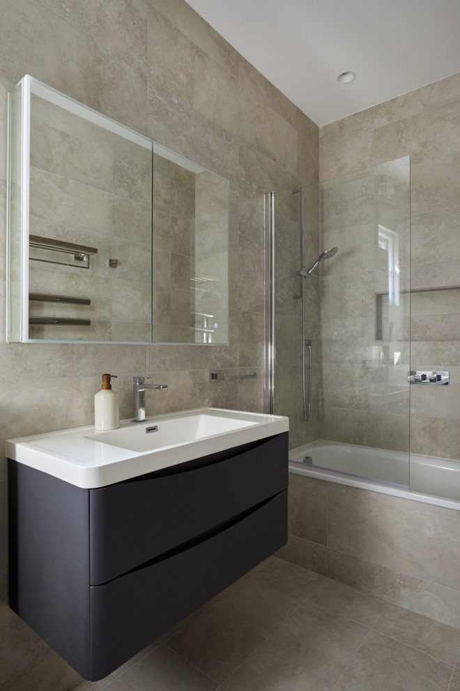 Design ideas for a mid-sized contemporary kids bathroom in London with grey cabinets, an alcove tub, a shower/bathtub combo, a wall-mount toilet, gray tile, porcelain tile, grey walls, porcelain floors, an integrated sink, grey floor, a hinged shower door, a niche, a single vanity, a floating vanity and flat-panel cabinets.