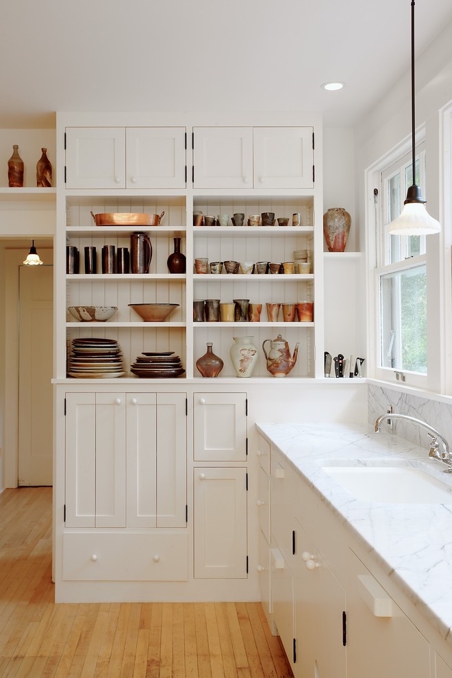 Photo of a traditional kitchen in Seattle with an undermount sink, white cabinets and light hardwood floors.