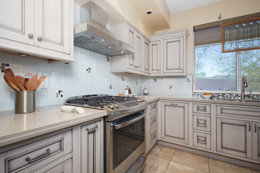 Inspiration for a large transitional l-shaped ceramic tile open concept kitchen remodel in Phoenix with an undermount sink, beaded inset cabinets, gray cabinets, quartz countertops, white backsplash, glass tile backsplash, black appliances and an island