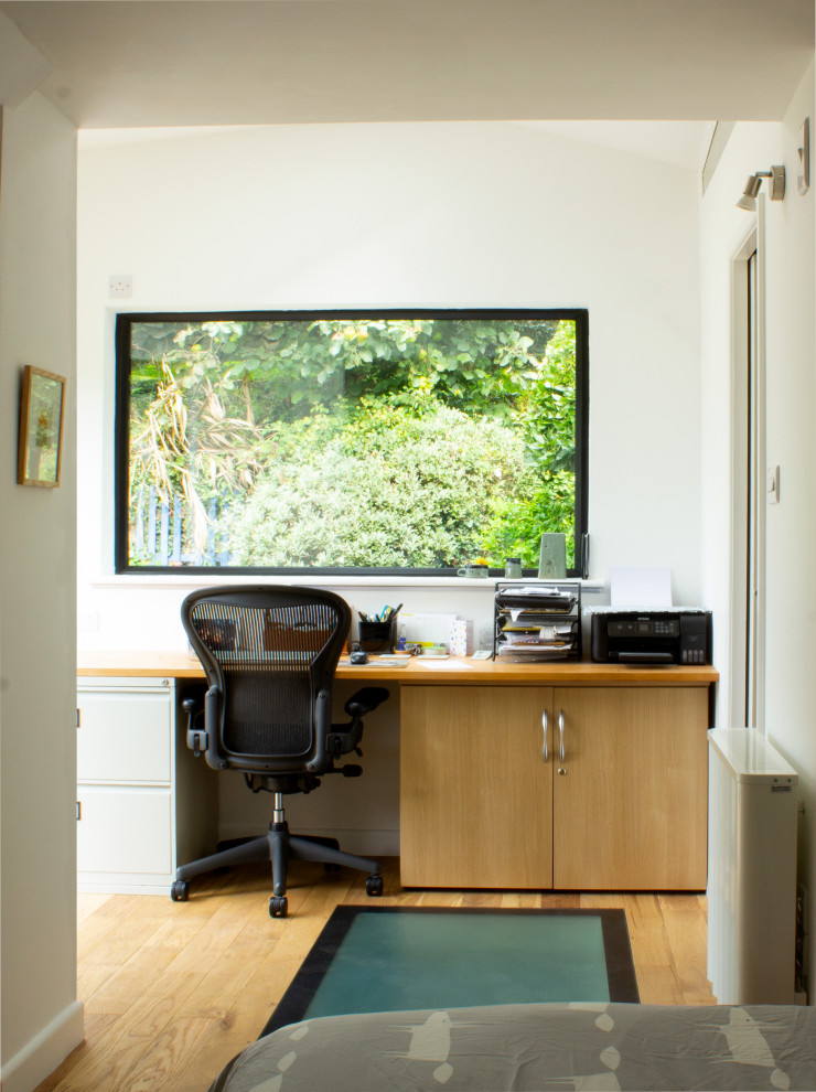 Small contemporary home studio in Devon with white walls, light hardwood floors, a freestanding desk, beige floor and coffered.