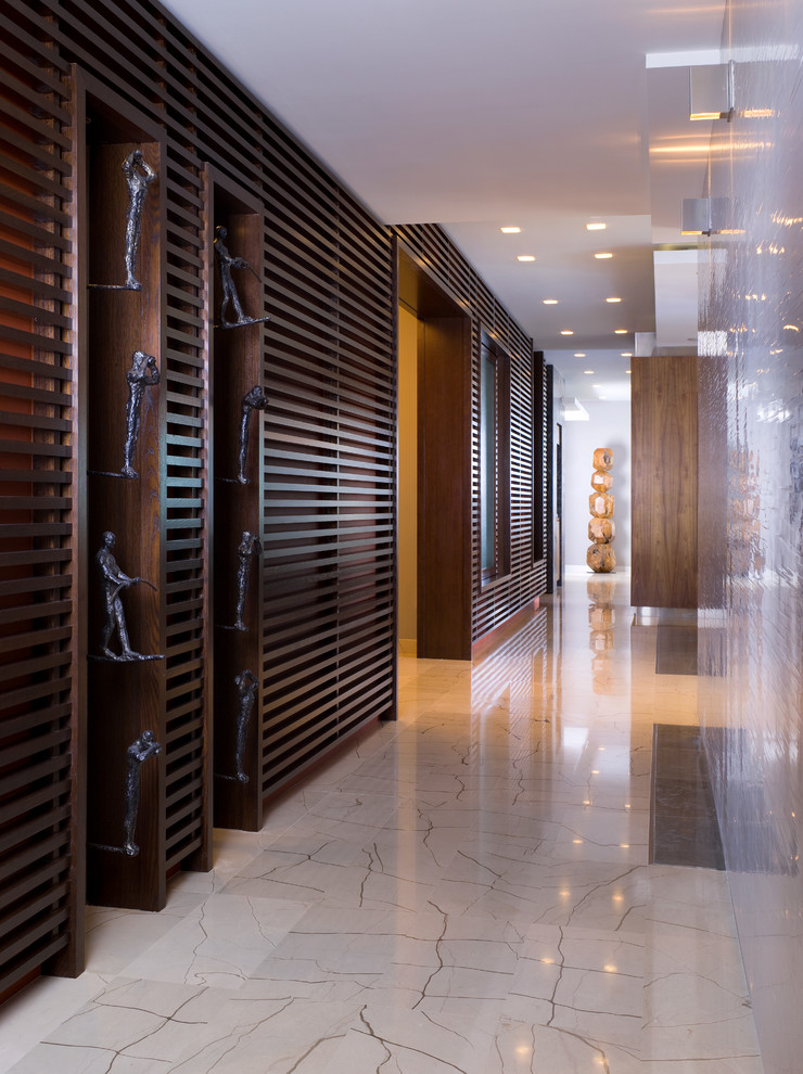 This is an example of a large contemporary hallway in Miami with beige walls and limestone floors.