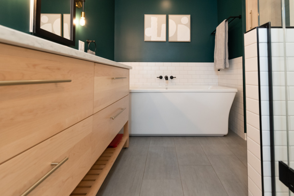 Inspiration for a transitional bathroom in Other with flat-panel cabinets, light wood cabinets, a freestanding tub, green tile, subway tile, ceramic floors, grey floor, a double vanity and a freestanding vanity.