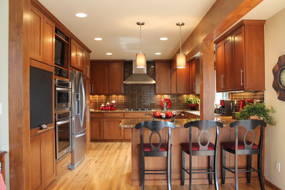 Large transitional u-shaped light wood floor eat-in kitchen photo in Denver with an undermount sink, flat-panel cabinets, dark wood cabinets, granite countertops, gray backsplash, glass tile backsplash, stainless steel appliances and a peninsula