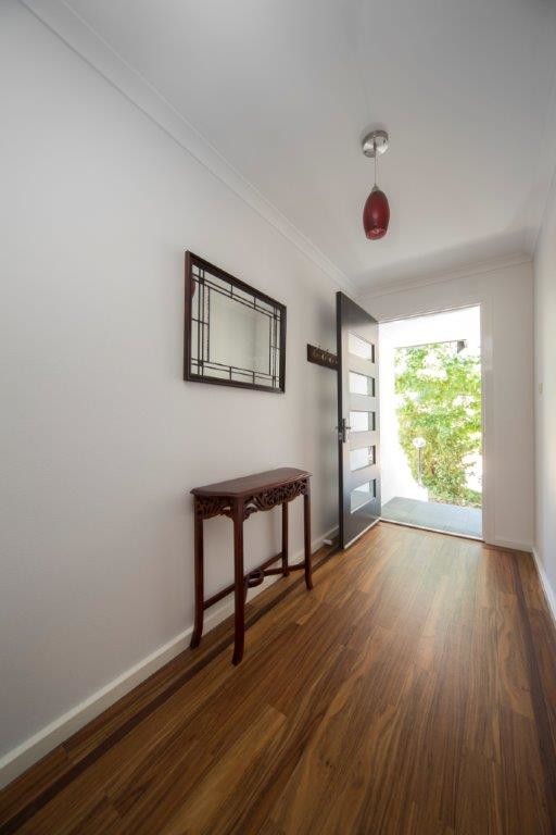 Inspiration for a small contemporary entry hall in Canberra - Queanbeyan with white walls, medium hardwood floors, a single front door and a black front door.