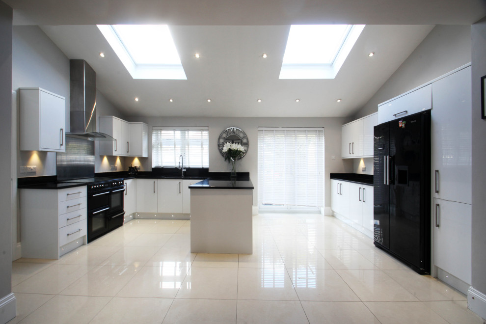 Medium sized modern l-shaped open plan kitchen in Cheshire with a double-bowl sink, flat-panel cabinets, white cabinets, granite worktops, metallic splashback, metal splashback, black appliances, porcelain flooring, a breakfast bar, beige floors and black worktops.
