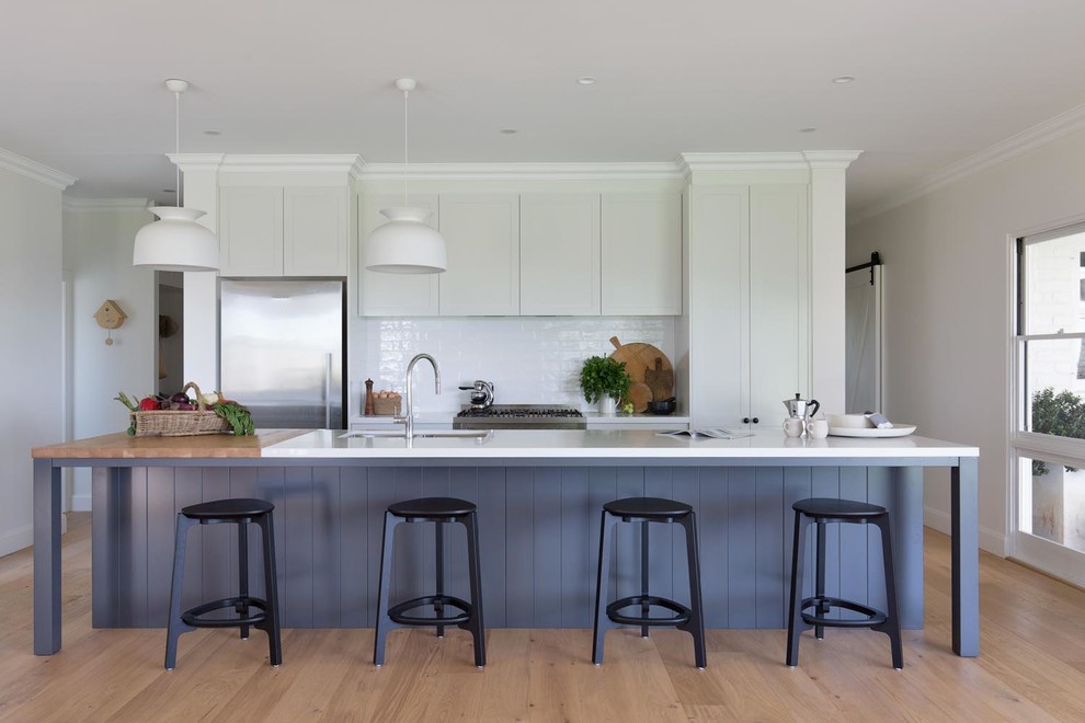 Design ideas for a large country galley eat-in kitchen in Wollongong with white cabinets, quartz benchtops, white splashback, ceramic splashback, stainless steel appliances, with island, white benchtop, an undermount sink, recessed-panel cabinets, medium hardwood floors and beige floor.