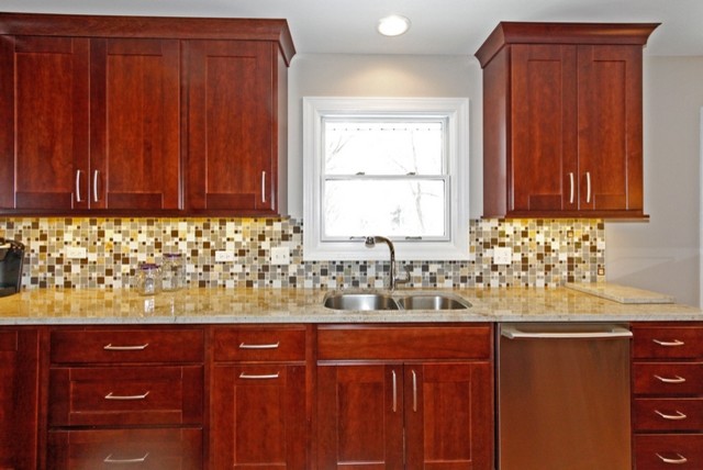 Eat-in kitchen - mid-sized transitional l-shaped medium tone wood floor eat-in kitchen idea in Chicago with an undermount sink, recessed-panel cabinets, medium tone wood cabinets, granite countertops, gray backsplash, glass tile backsplash, stainless steel appliances, gray walls and an island