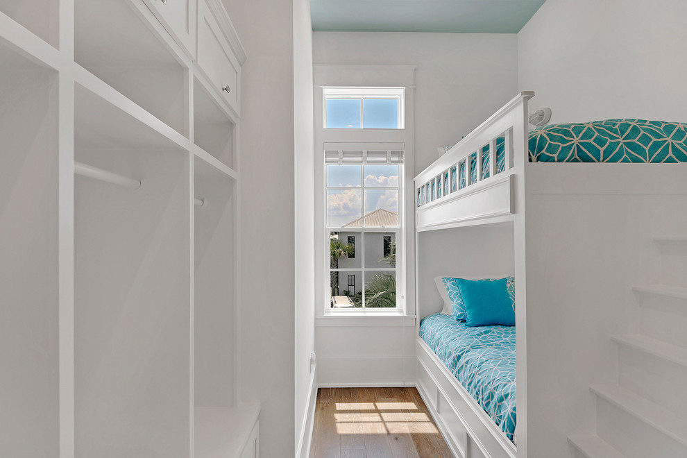 Design ideas for a mid-sized beach style kids' bedroom for kids 4-10 years old and girls in Miami with white walls and light hardwood floors.