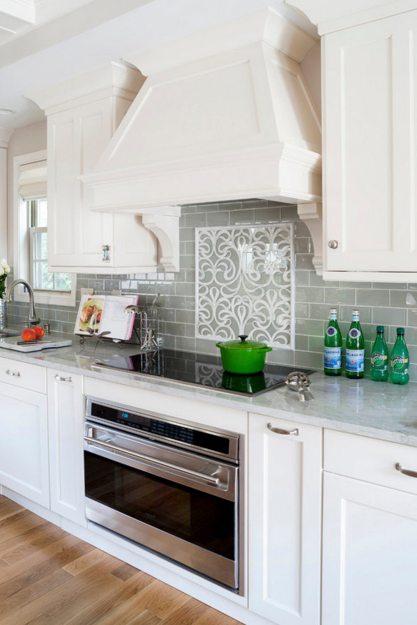 Design ideas for a traditional kitchen in Other with raised-panel cabinets, white cabinets, solid surface benchtops, green splashback, glass tile splashback, stainless steel appliances and medium hardwood floors.