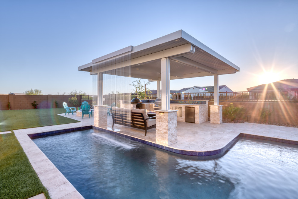 This is an example of a large modern backyard rectangular natural pool in Phoenix with a water feature and concrete pavers.