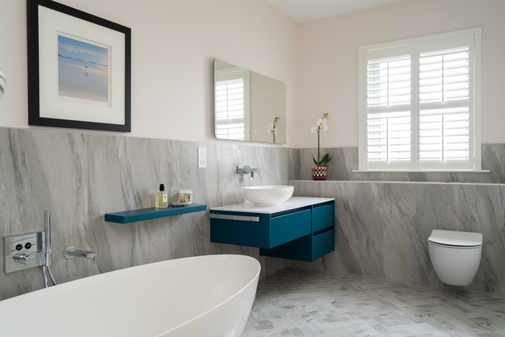 Design ideas for a mid-sized contemporary bathroom in Belfast with flat-panel cabinets, blue cabinets, a freestanding tub, gray tile, porcelain tile, porcelain floors, a console sink, grey floor, a single vanity and a floating vanity.