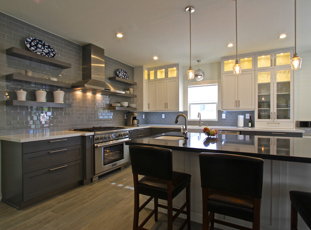 Example of a transitional porcelain tile kitchen design in Orange County with glass tile backsplash and an island