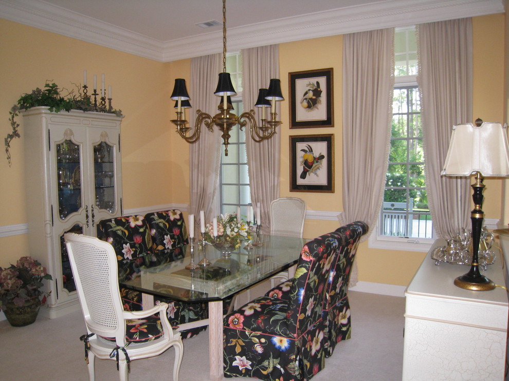 This is an example of a mid-sized tropical separate dining room in Charleston with yellow walls and carpet.