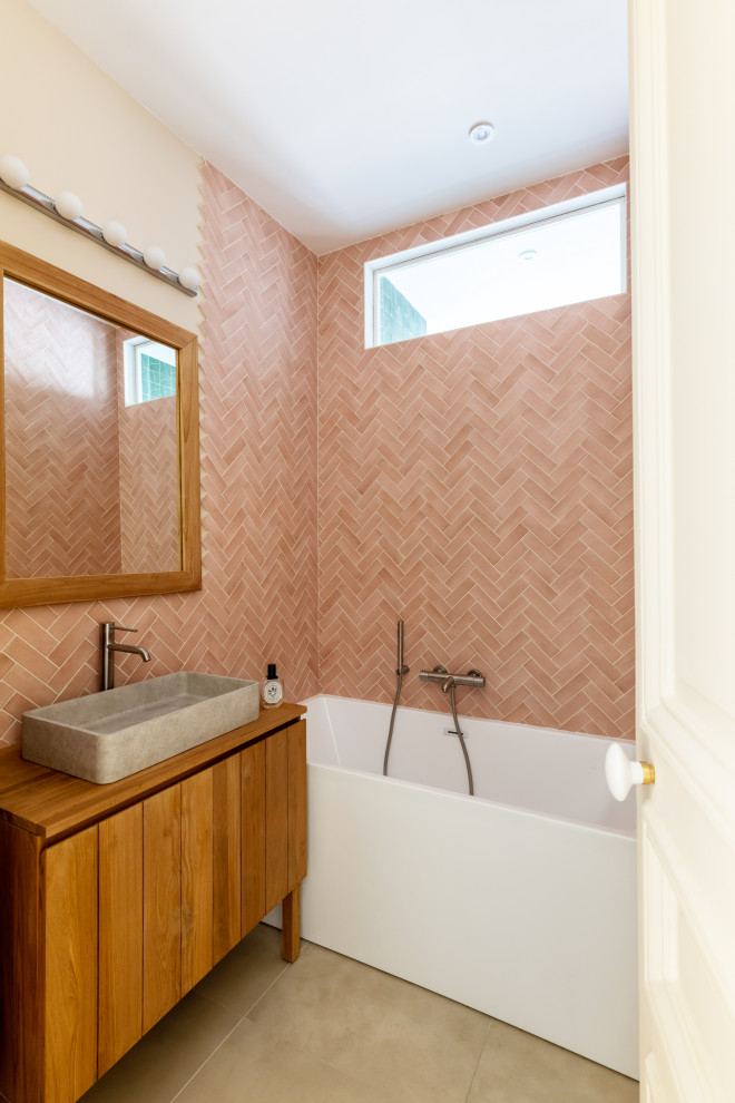 Exemple d'une petite salle de bain beige et blanche rétro en bois brun pour enfant avec un placard à porte affleurante, une baignoire encastrée, un carrelage rose, des carreaux en terre cuite, un mur rose, un sol en carrelage de céramique, un lavabo posé, un plan de toilette en bois, un sol beige, un plan de toilette marron, une fenêtre, meuble simple vasque et meuble-lavabo suspendu.