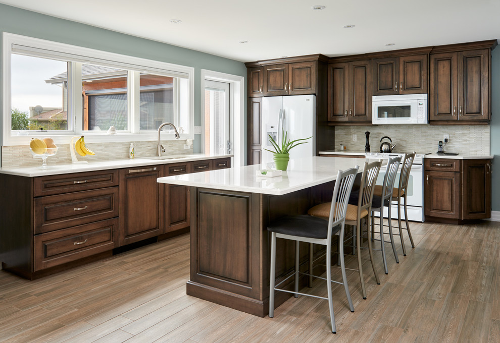 Design ideas for a large traditional l-shaped open plan kitchen in Toronto with an undermount sink, raised-panel cabinets, medium wood cabinets, quartz benchtops, beige splashback, mosaic tile splashback, white appliances, porcelain floors and with island.