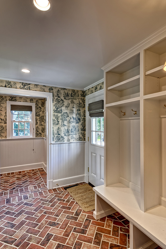 Mid-sized traditional single-wall utility room in New York with shaker cabinets, white cabinets, beige walls, brick floors, a side-by-side washer and dryer and brown floor.
