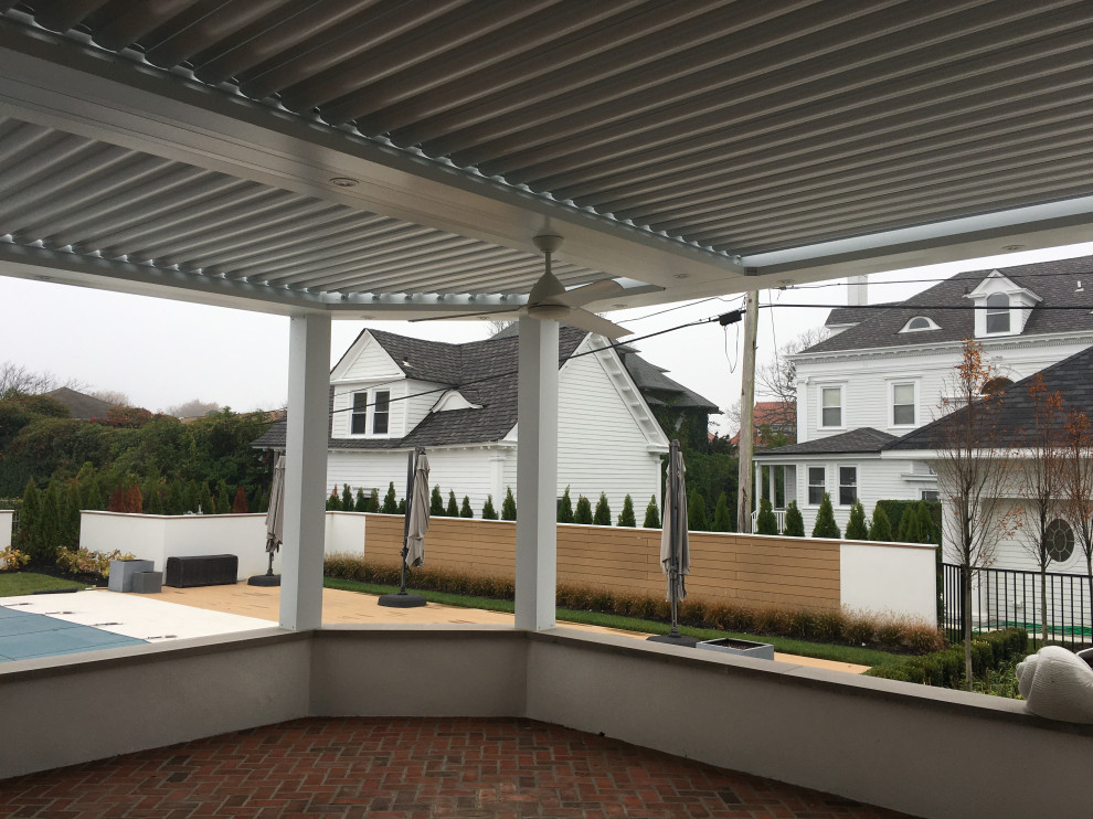 This is an example of a large modern backyard patio in Newark with brick pavers and a pergola.
