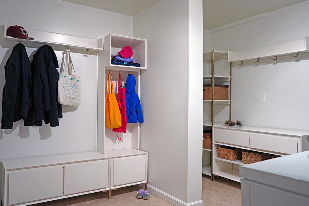 This is an example of a small modern single-wall laundry room in San Francisco with a single-bowl sink, flat-panel cabinets, white cabinets and a concealed washer and dryer.