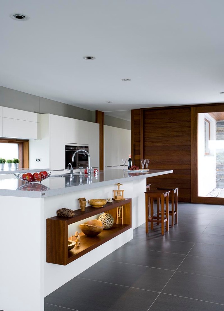 Photo of a large contemporary single-wall open plan kitchen in Other with a single-bowl sink, flat-panel cabinets, white cabinets, granite benchtops, white splashback, glass sheet splashback, stainless steel appliances, ceramic floors and with island.