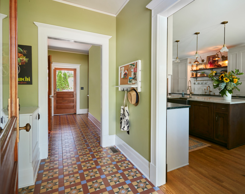 Foto de distribuidor tradicional de tamaño medio con paredes verdes, suelo de baldosas de cerámica, puerta de madera en tonos medios y suelo multicolor