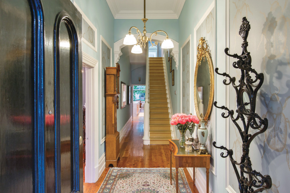 Esempio di un corridoio chic di medie dimensioni con pareti blu, parquet chiaro, una porta singola, una porta nera, pavimento marrone e boiserie