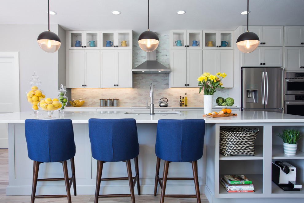 Transitional galley light wood floor and beige floor kitchen photo in Austin with an undermount sink, shaker cabinets, gray cabinets, beige backsplash, stainless steel appliances, an island and white countertops