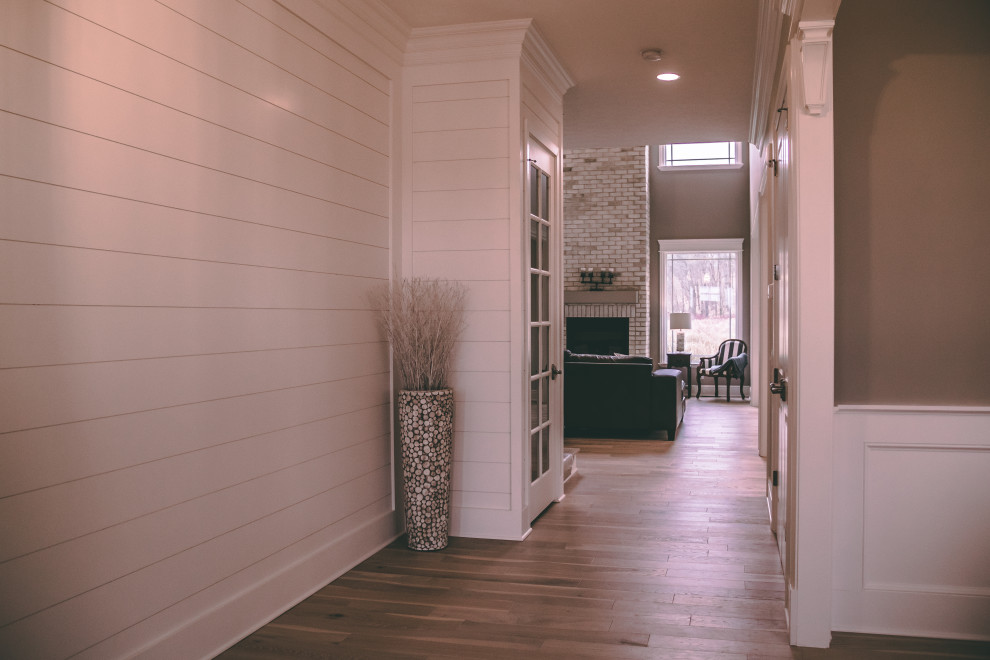 Mid-sized transitional light wood floor and shiplap wall foyer photo with beige walls