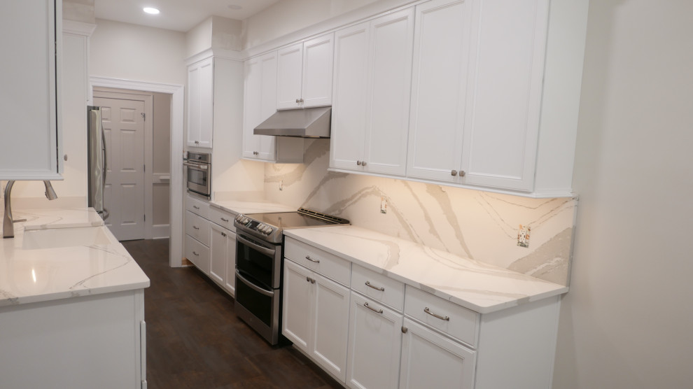 Inspiration for a mid-sized transitional galley laminate floor and multicolored floor eat-in kitchen remodel with a farmhouse sink, shaker cabinets, white cabinets, quartz countertops, white backsplash, quartz backsplash, stainless steel appliances and white countertops