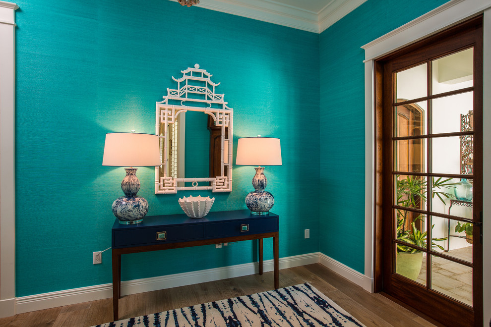 Inspiration for a mid-sized tropical foyer in Miami with blue walls, light hardwood floors, a single front door, a dark wood front door and beige floor.