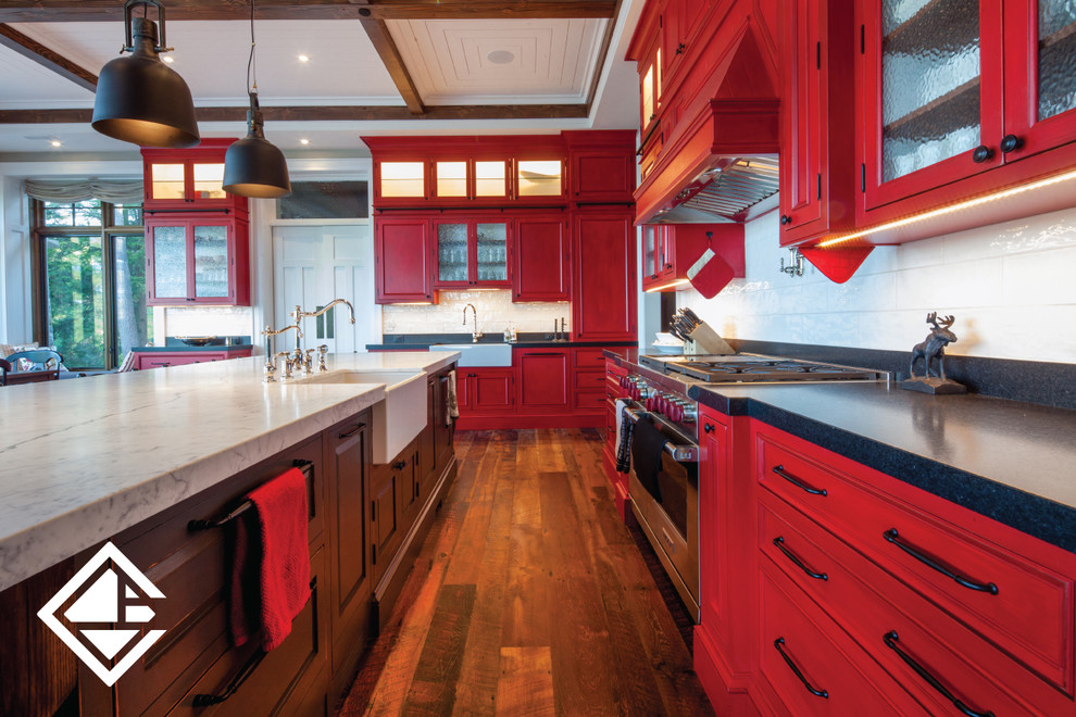 Example of a huge mountain style l-shaped medium tone wood floor eat-in kitchen design with a farmhouse sink, raised-panel cabinets, red cabinets, granite countertops, white backsplash, stainless steel appliances and an island