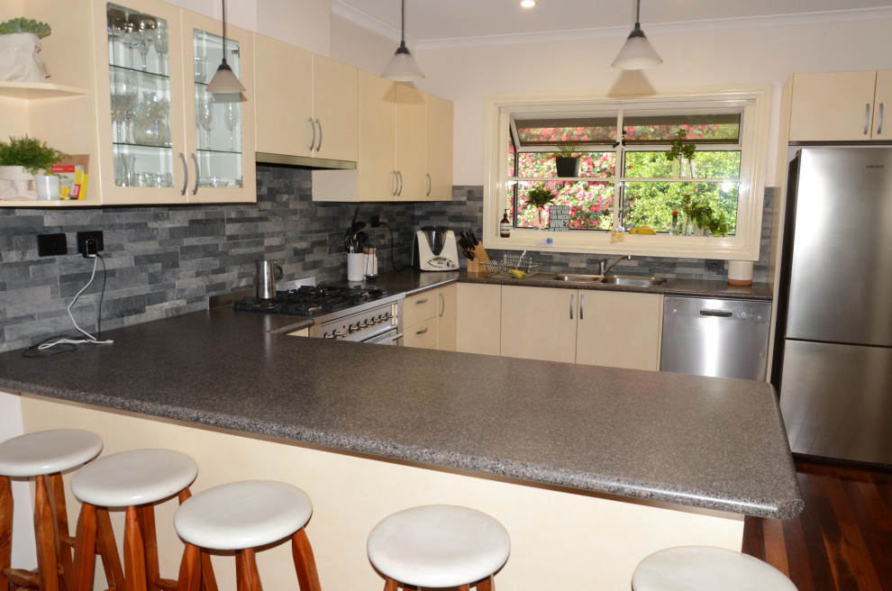 Inspiration for a mid-sized contemporary u-shaped eat-in kitchen in Melbourne with a double-bowl sink, yellow cabinets, quartz benchtops, grey splashback, slate splashback, stainless steel appliances, with island and grey benchtop.