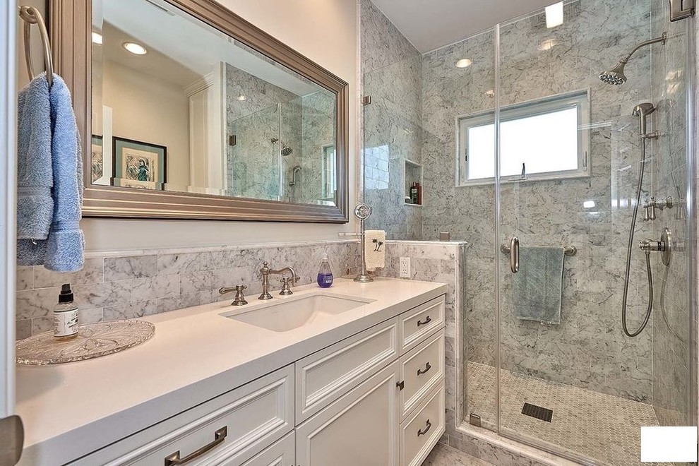 This is an example of a mid-sized traditional 3/4 bathroom in Los Angeles with beaded inset cabinets, white cabinets, a freestanding tub, a curbless shower, a one-piece toilet, gray tile, ceramic tile, beige walls, ceramic floors, a trough sink, engineered quartz benchtops, grey floor, a hinged shower door and white benchtops.
