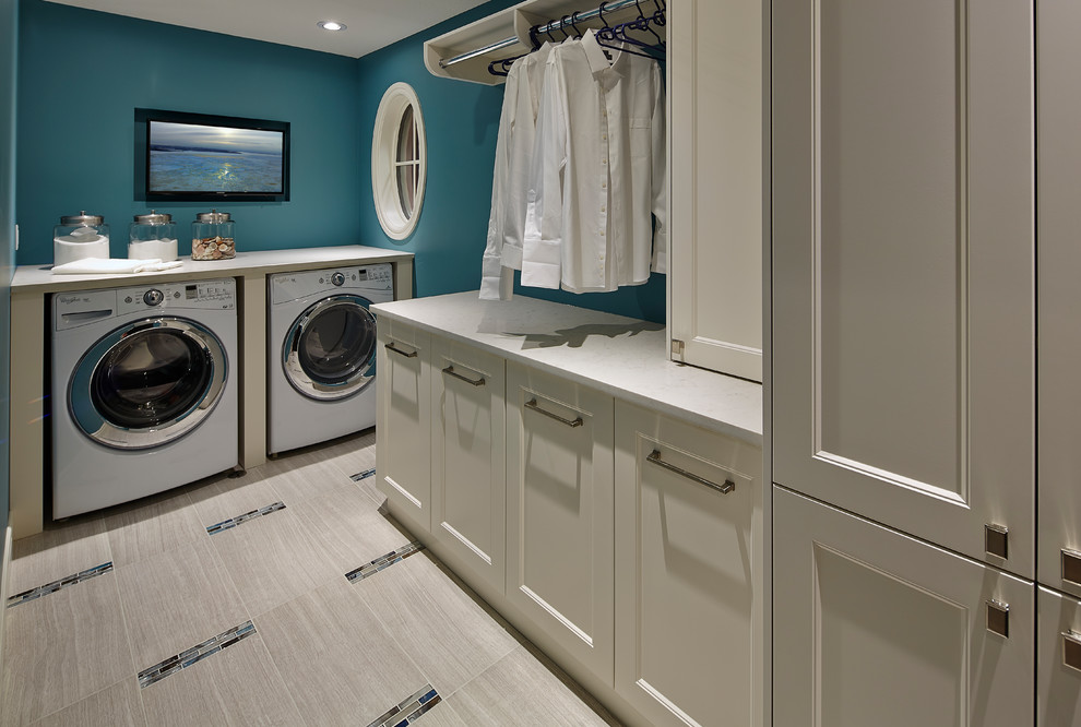 Photo of a mid-sized contemporary l-shaped dedicated laundry room in Other with white cabinets, blue walls, a side-by-side washer and dryer, recessed-panel cabinets, solid surface benchtops and porcelain floors.