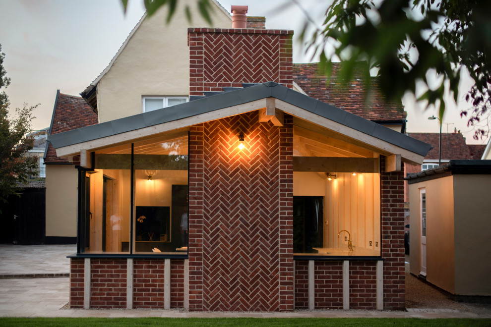 Esempio della facciata di una casa contemporanea con rivestimento in mattoni e copertura in metallo o lamiera