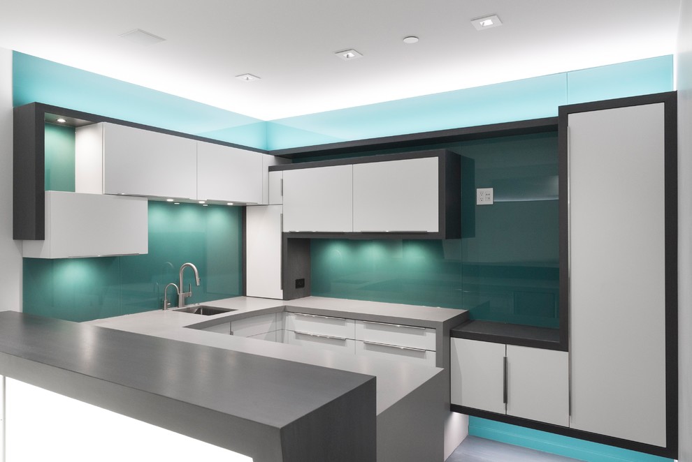 Inspiration for a mid-sized contemporary u-shaped open plan kitchen in Salt Lake City with an undermount sink, flat-panel cabinets, white cabinets, quartz benchtops, green splashback, glass sheet splashback, white appliances and a peninsula.