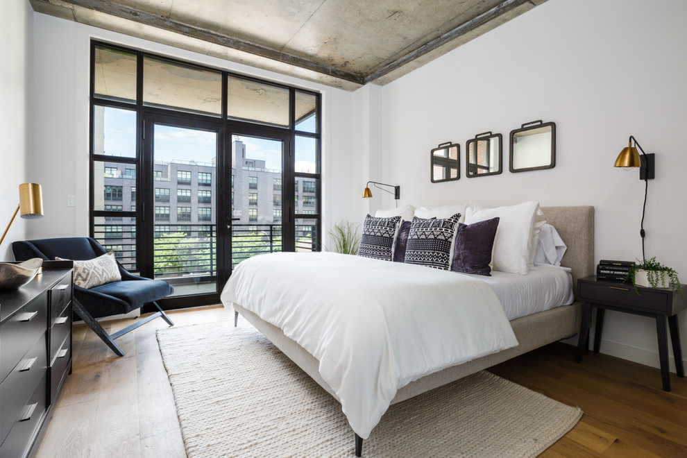 Mid-sized contemporary guest bedroom in New York with white walls, light hardwood floors and brown floor.