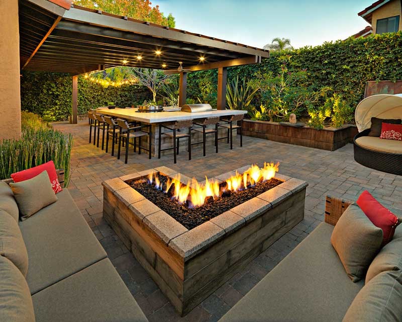 Small modern backyard patio in San Diego with an outdoor kitchen, brick pavers and a pergola.