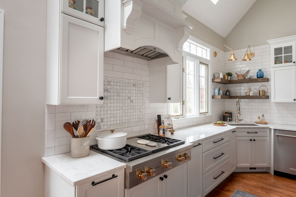 ボストンにある巨大なトランジショナルスタイルのおしゃれなキッチン (アンダーカウンターシンク、シェーカースタイル扉のキャビネット、白いキャビネット、クオーツストーンカウンター、白いキッチンパネル、サブウェイタイルのキッチンパネル、シルバーの調理設備、濃色無垢フローリング、茶色い床、白いキッチンカウンター、三角天井) の写真