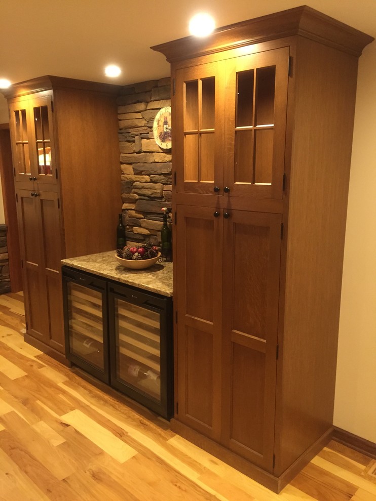 Photo of a mid-sized traditional single-wall wet bar in Philadelphia with dark wood cabinets, quartz benchtops, stone tile splashback, shaker cabinets, light hardwood floors and brown floor.