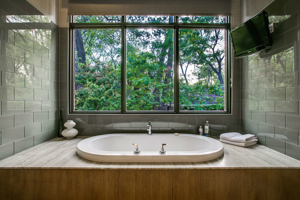 This is an example of a contemporary master bathroom in Dallas with a drop-in tub, gray tile and glass tile.