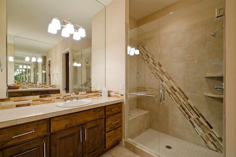 Photo of a large transitional 3/4 bathroom in Denver with a drop-in sink, dark wood cabinets, an alcove shower, white walls, raised-panel cabinets, tile benchtops, a one-piece toilet, beige tile, porcelain tile and porcelain floors.