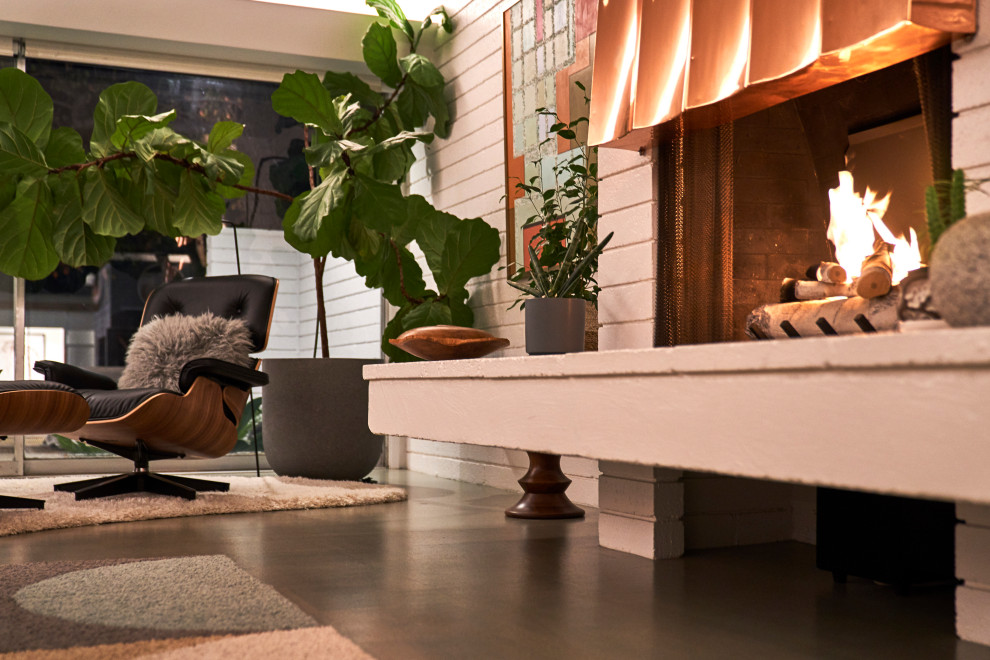 Photo of a mid-sized midcentury open concept living room in San Diego with white walls, cork floors, a standard fireplace, a metal fireplace surround, a concealed tv, grey floor and brick walls.