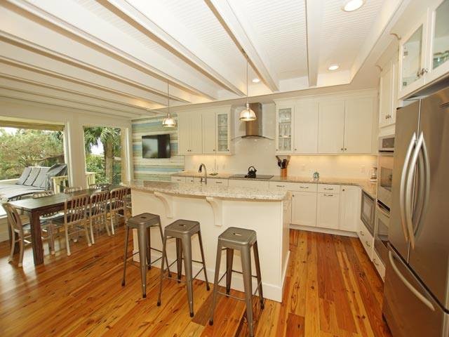 Example of a mid-sized transitional single-wall medium tone wood floor and gray floor eat-in kitchen design with an undermount sink, shaker cabinets, white cabinets, granite countertops, stainless steel appliances and an island