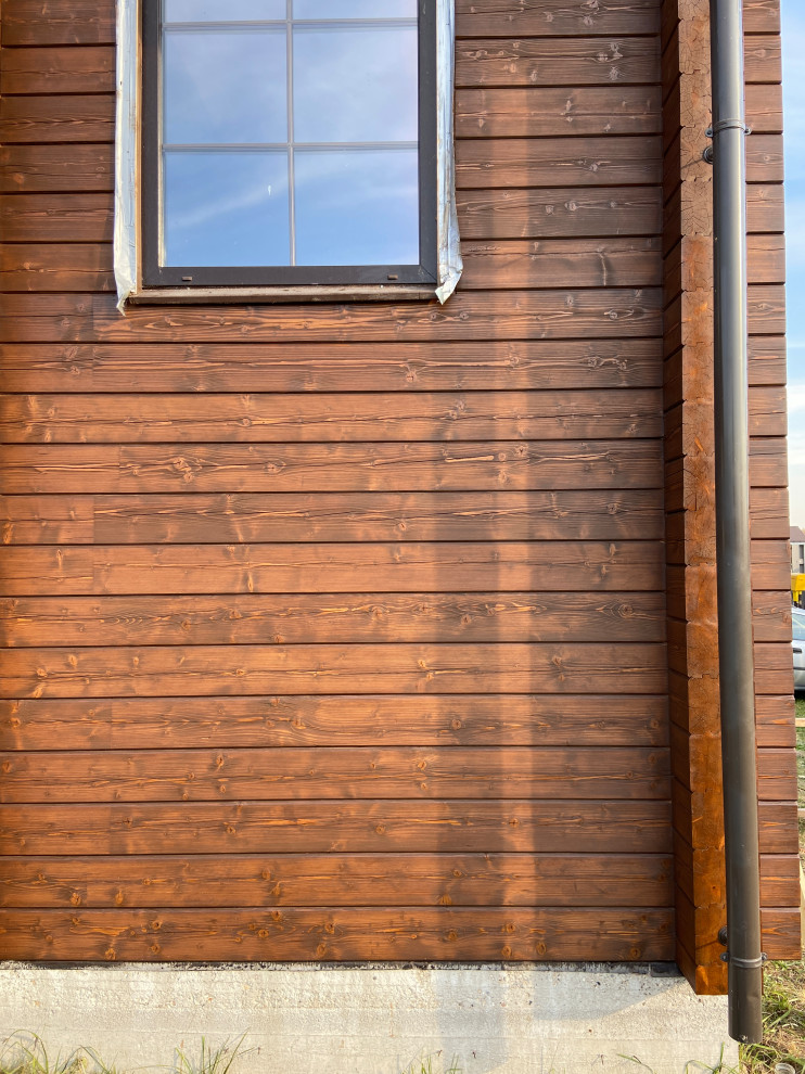 Esempio della villa marrone contemporanea a due piani di medie dimensioni con rivestimento in legno, tetto a mansarda, copertura a scandole e tetto marrone