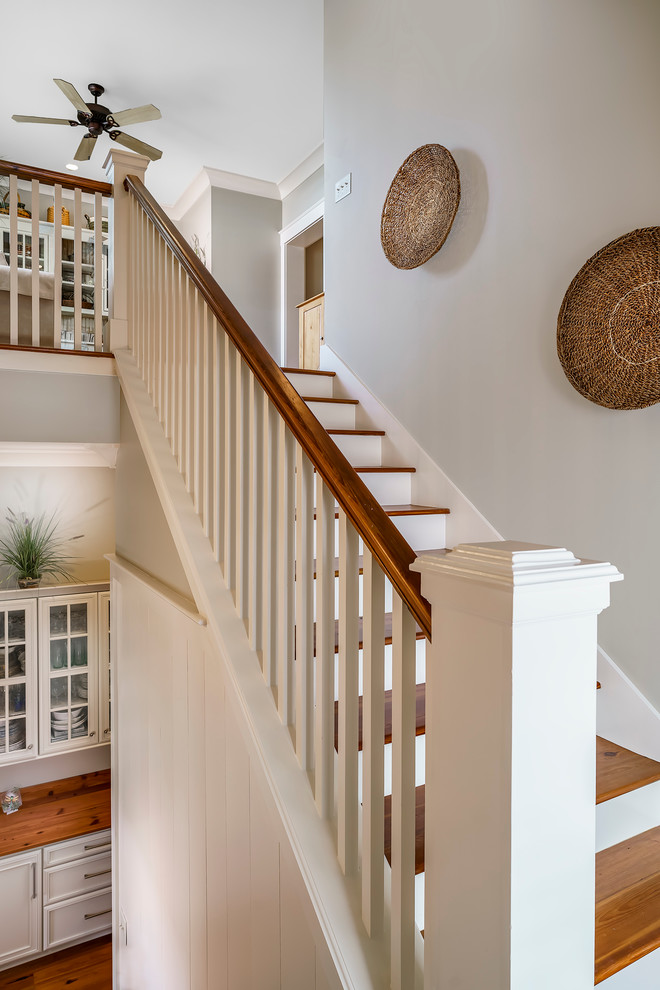 Large transitional wood l-shaped staircase in Charleston with painted wood risers and wood railing.