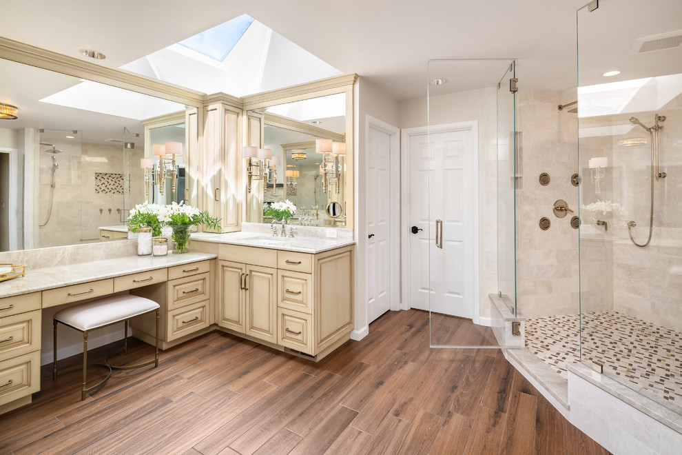 Large transitional master bathroom in Seattle with raised-panel cabinets, distressed cabinets, a double shower, a one-piece toilet, beige tile, marble, beige walls, ceramic floors, an undermount sink, quartzite benchtops, brown floor, a hinged shower door and beige benchtops.