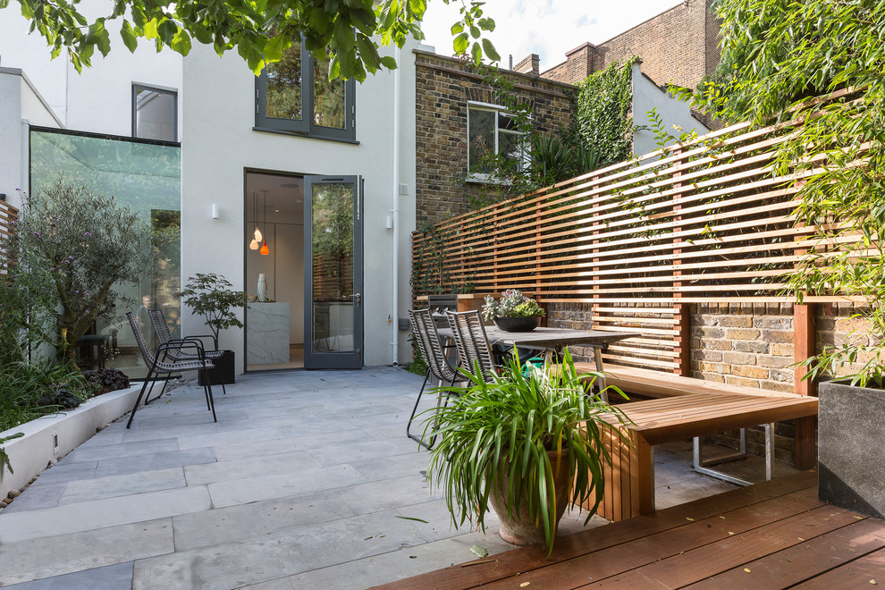 This is an example of a mid-sized contemporary backyard patio in London with concrete pavers and no cover.