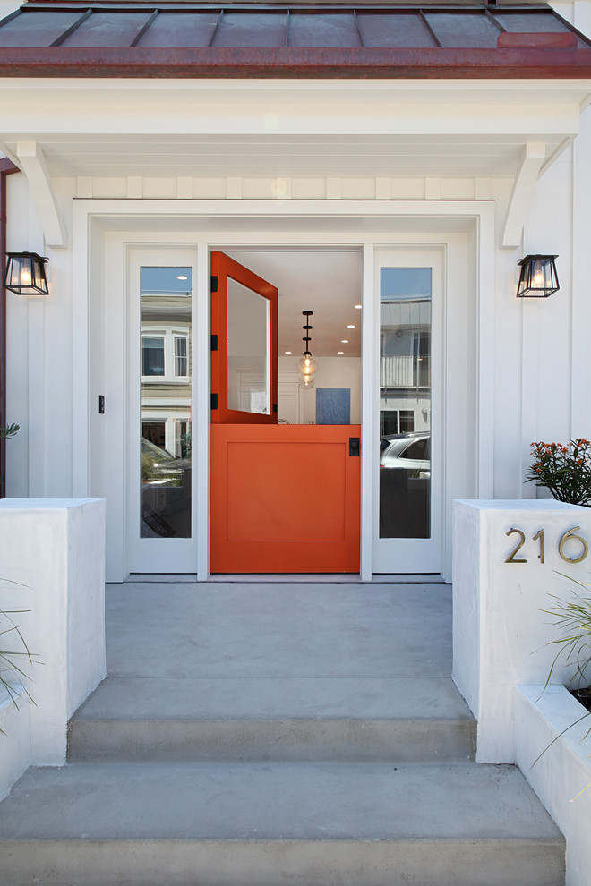 This is an example of a mid-sized beach style front door in Orange County with a dutch front door, an orange front door, white walls, concrete floors and grey floor.